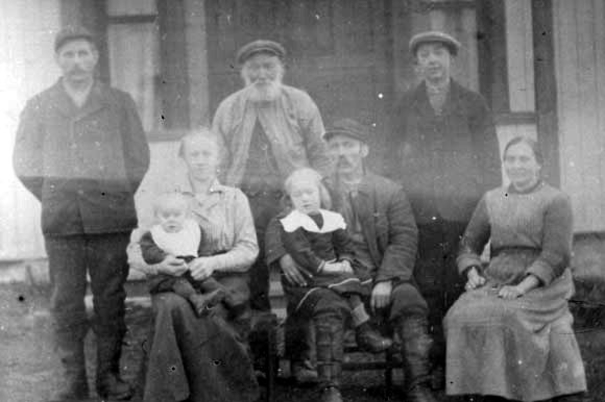 Anno Domkirkeodden, GRUPPE: 8, ARBEIDSFOLK OG HUSBONDSFOLK FORAN INNGANGSDØRA HUSE NORDRE, BAK FRA VENSTRE:MAGNUS MARTINSEN, JAKOB LARSEN, MARTIN, SITTENDE:JULIE GRØHOLT MED IVAR PÅ FANGET, JOHAN GRØHOLTMED ALVILDE PÅ FANGET, MARIE LARSEN,