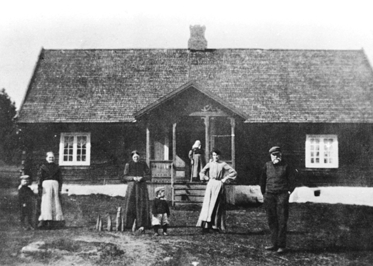 Anno Domkirkeodden, EKSTERIØR: BOLIG, EVENRUDBAKKEN, GRUPPE: 7 VOKSNE OG BARN FORAN, FRA VENSTRE: OLA BEKKEN, MATHEA EVENRUDBAKKEN, MARIE EVENRUDBAKKEN, ARNE BÆKKEN FØDT: 15. 03. 1908, MARTHE EVENRUDBAKKEN (HEKNERØNNINGEN) FØDT: 1817, HULDA BAKKEN FØDT: 03. 09. 1879, KRISTIANSEN EVENRUDBAKKEN FØDT: 06. 03. 1840