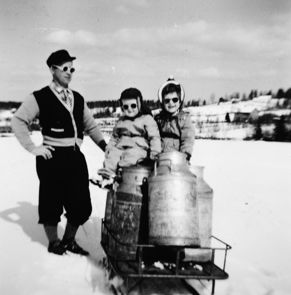 Ukjent, Jølstad i Vallset vinteren 1954. Her hentes mjølkekjelene fra vegen og tilbake til gården.. Kjerra hadde meier om vinteren og hjul på sommeren. F. v. Henry Foss f. 1919, Finn Ove Foss f. 1952 og Eva Bodil Foss f. 1949.