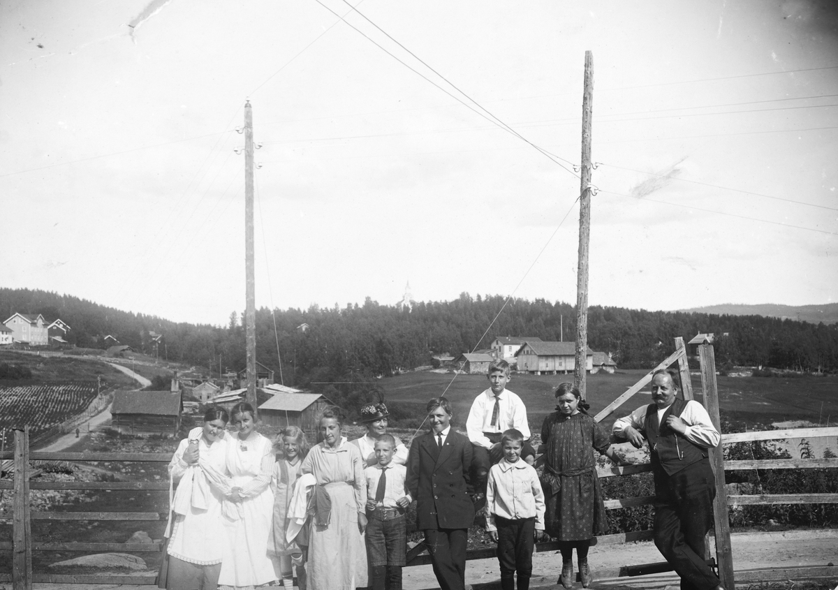 Ukjent, Ved grinda utenfor Solhaug under Vestgård på Tangen ca. 1915-1920. Øverst t. v. Lundby-butikken ved Vik gård. T. h. på bildet Landhandler Aksel J. Jansen, i midten med dress Arne Håvard Jansen, helt t. v. Ingrid Dorothea Finstad. Flere opplysninger se boka "Handelssteder i Stange" skrevet av Jan Ar…