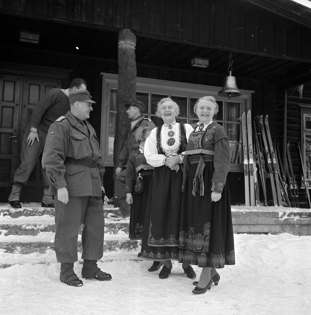 Adolf Skjegstad, KONG OLAV I MILITÆRUNIFORM I SAMTALE MED TO KVINNER I BUNAD, FOLKEDRAKTER.