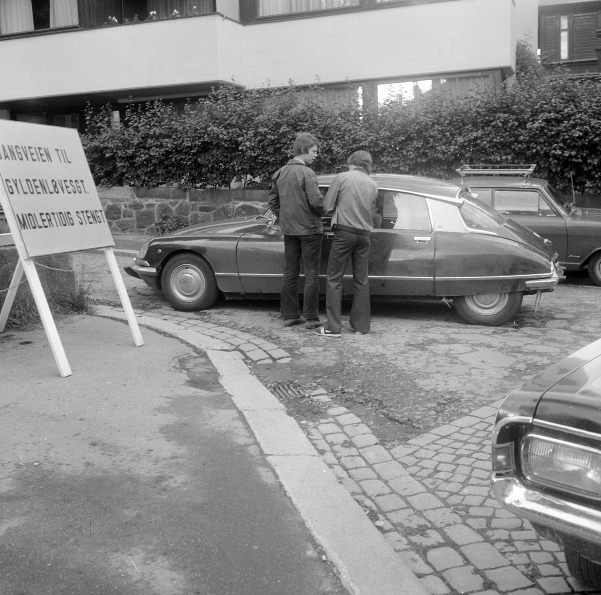 Adolf Skjegstad, Gr. 2 menn, stående ved Citroën DS, 1968-75 model. Nærmest synes hjørne av Opel Rekord C 1967-ca. 71, og i bak kant av bildet en Opel Kadett ca. 1967-71.
