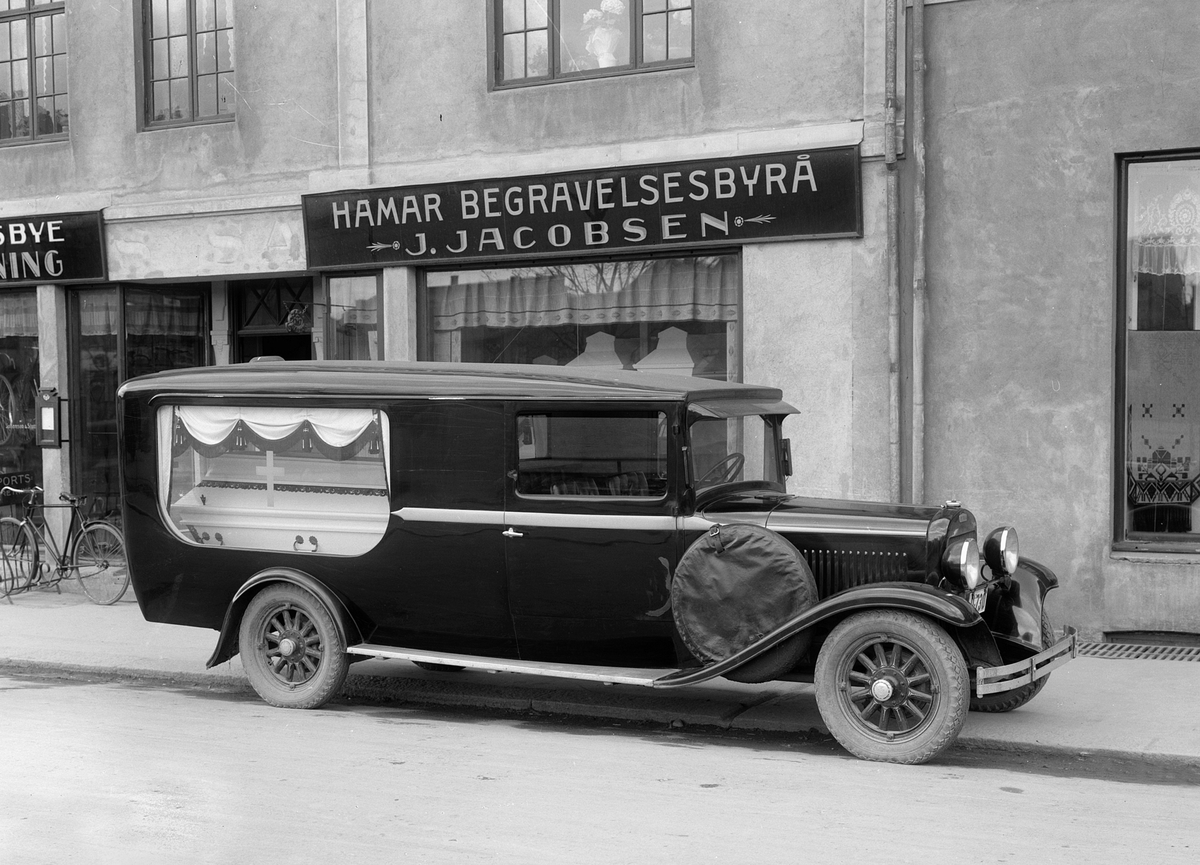Christian Grundseth, Hamar Begravelsesbyrå. J. JACOBSENS BEGRAVELSESBYRÅ. LIKBIL FORAN BUTIKKEN I TORGGATA. Begravelsesbil registreringsnr. D-730. I Norges Bilbok 1935 står D-730 på J. Jacobsen, Hamar, som likbil, merke ikke oppgitt, årsmodell 1933. (I Bilboken 1930 er nummeret ikke i bruk.)