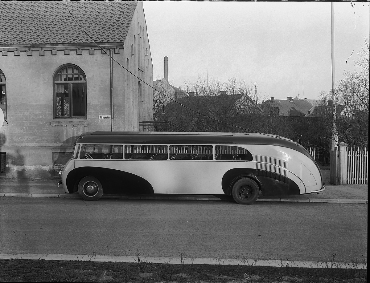 Christian Grundseth, BUSS, DODGE 1938 MED FOLDETAK. E-329. CHASSISET LEVERT AV OLRUD AUTO, OMBYGD TIL HEKKMOTOR OG PÅBYGD KAROSSERI AV BRUMUNDDAL MEK. VERKSTED & STØPERI FOR RUTEBILEIER JOHAN ANDERSEN, JEVNAKER (JEVNAKER BILRUTER). BUSSEN BLE ØDELAGT UNDER KAMPENE I APRIL 1940. FOTOGRAFERT FORAN YNGLINGEN I KIRKEGATA. …