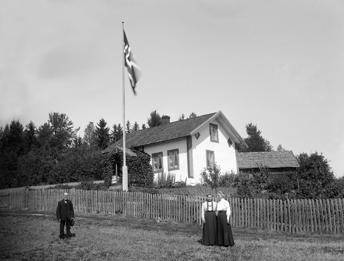 Martin Finborud, HØIBY. NES, Ringsaker. EKSTERIØR. FORAN LÆRER GUDBRAND OLSEN OG DØTRENE KRISTINE OG SIGRID OLSEN. Flagg, flaggstang.