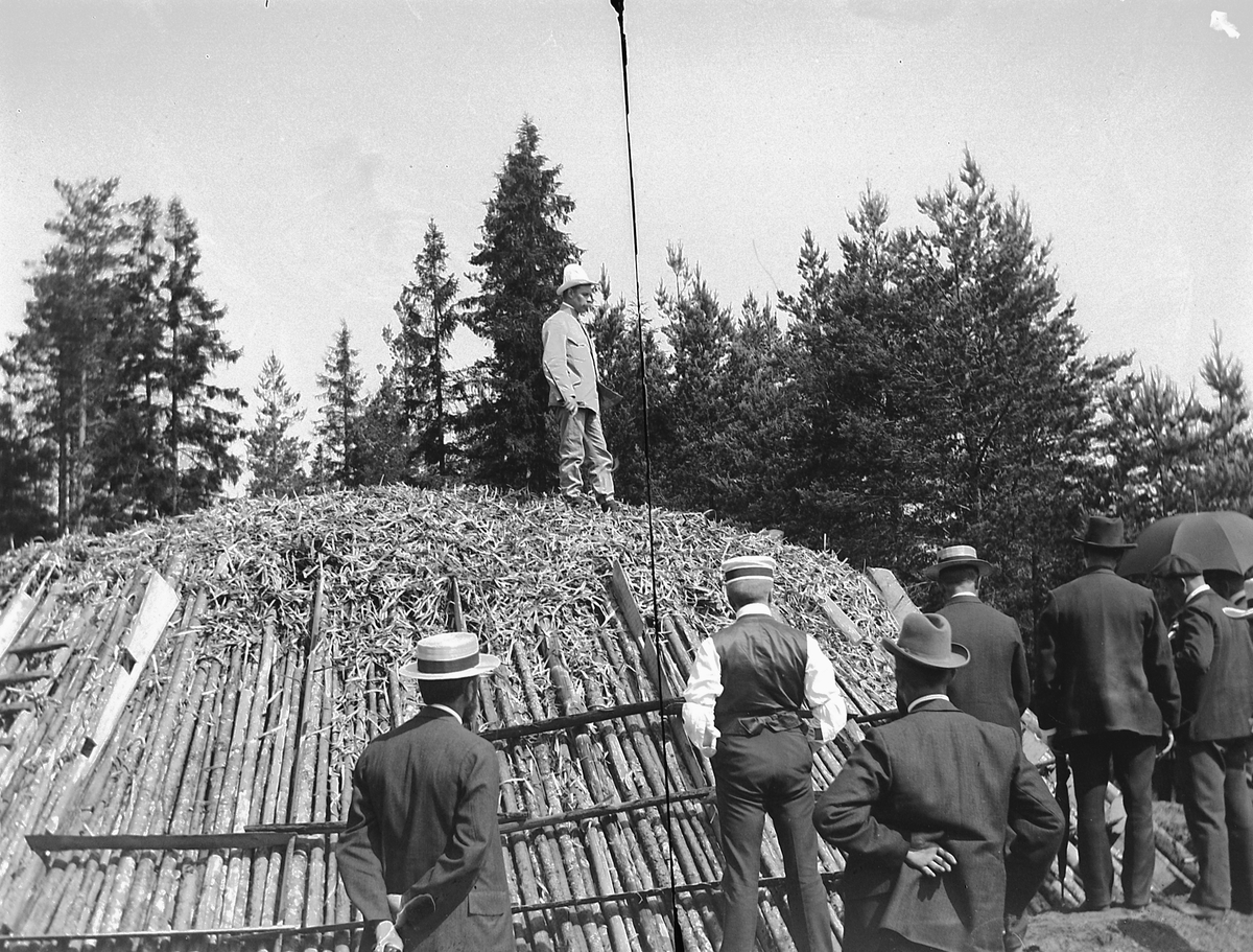 Ole Hansen Løken, TJÆREMILE, MOELVEN BRUG, UKJENTE PERSONER. BRENNING AV TREKULL. DEN SVENSKE RALLAREN LINDSKOG DELTOK I UTBYGGINGEN AV JERNBANEN GJENNOM RINGSAKER OG KUNNE KUNSTEN MED TREKULLBRENNING. STYRET I MOELVEN BRUGINSPISERER FERDIG TILDEKKET MILE KLAR TIL OPPTENNING. UKJENTE.
