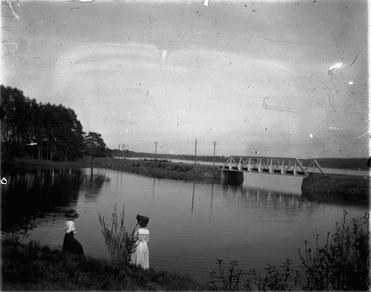 Johs. (Johannes) Johannessen, To kvinner ved vannkanten. Diesen bro i Vang, Hamar til høyre.