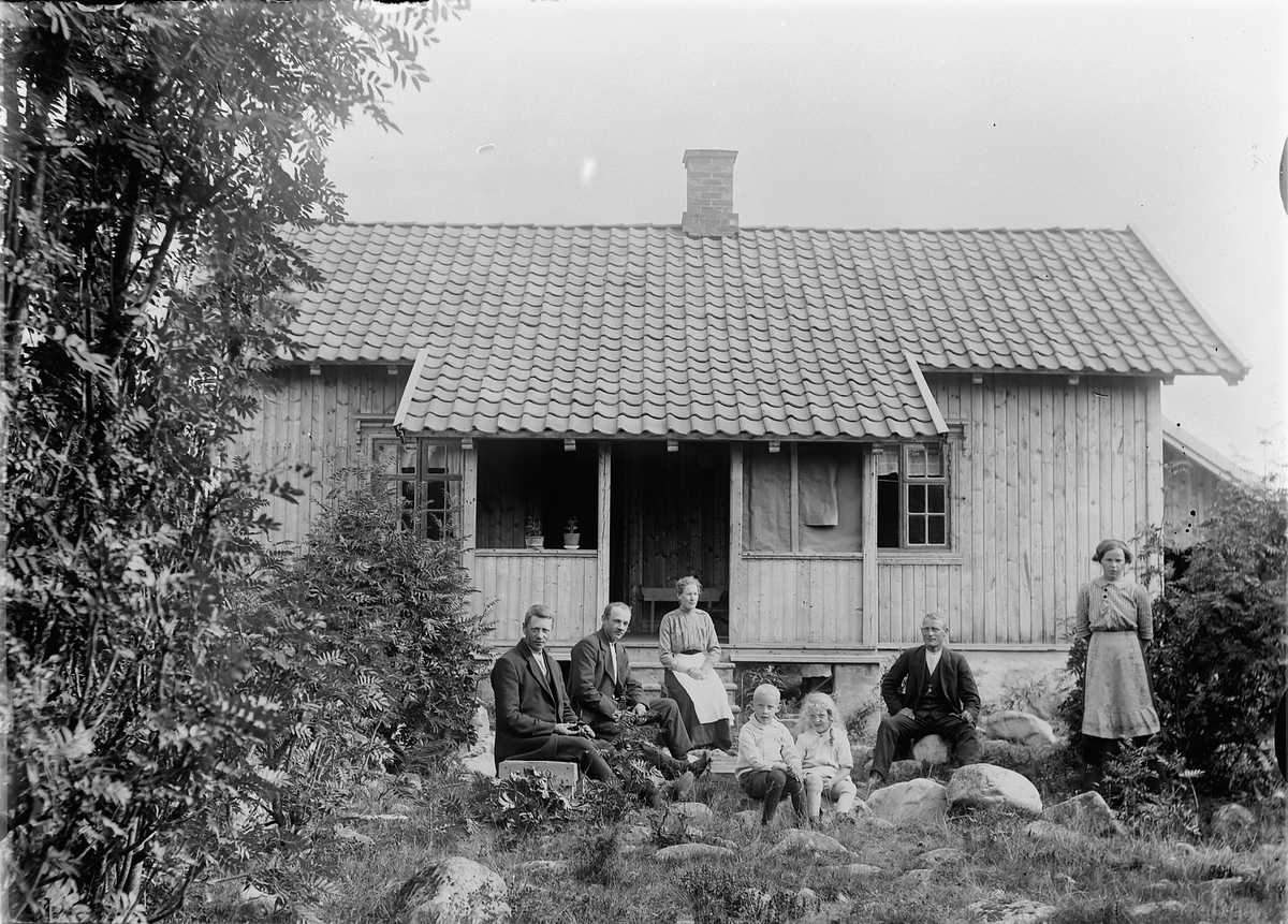 Mina Skraastad, Tre menn, to kvinner, og to barn foran et hus.