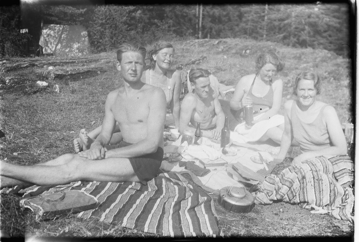 Håkon Prestkværn, Gruppe menn og kvinner soler seg på teppe.