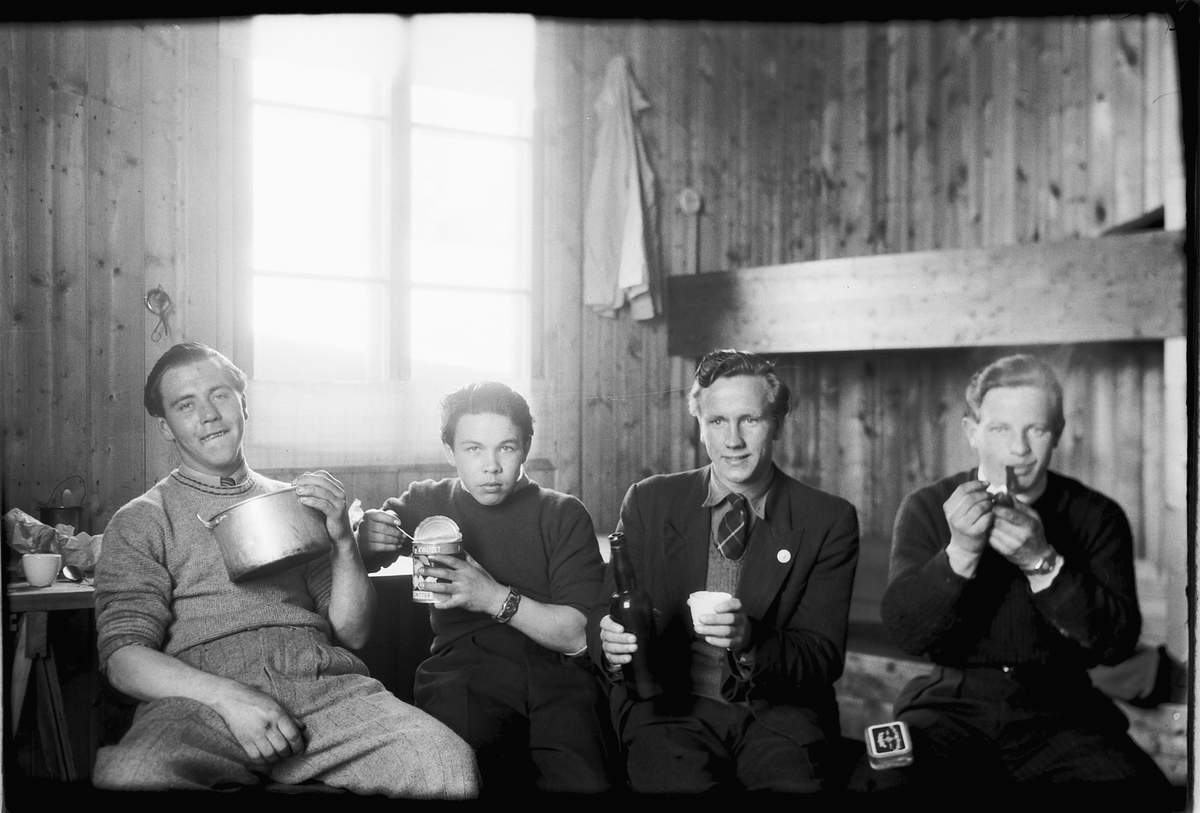 Håkon Prestkværn, Interiør, hytte. Fire ukjente menn spiser, drikker og røyker pipe.