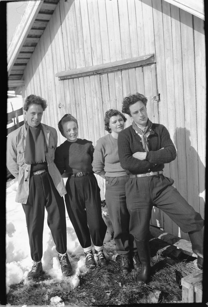 Håkon Prestkværn, To ukjente menn og kvinner foran et uthus.