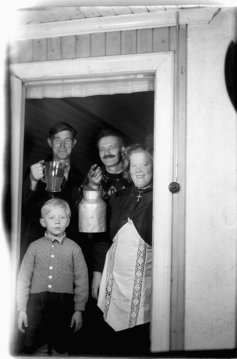 Håkon Prestkværn, Familie gruppe står i døråpningen med melkespann og mugge. Foran står Birger Aamodt og mor Astrid. Karene bakenfor er Martinus Gjerdingen og Alfred Syversen.