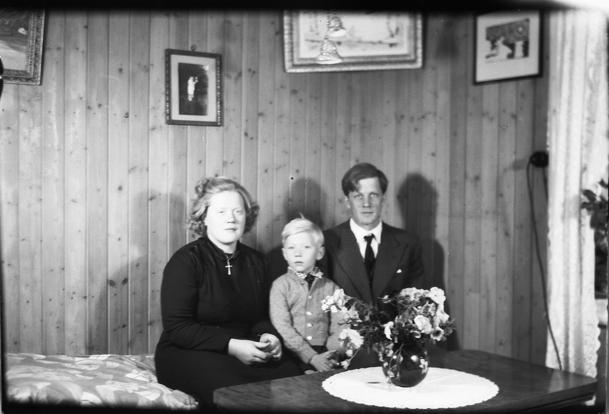 Håkon Prestkværn, Interiør, stue. Astrid, Birger og Olav Aamodt sittende på en sofa.