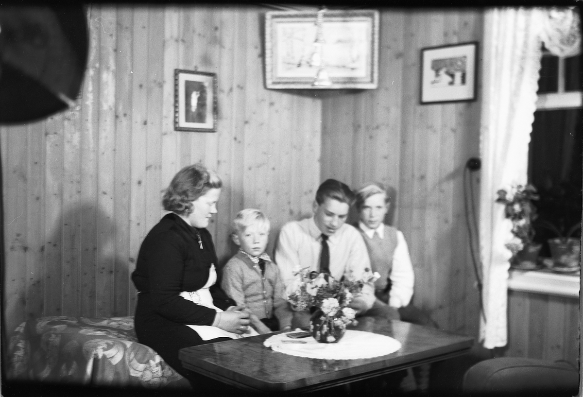 Håkon Prestkværn, Interiør, stue. Ukjent kvinne sammen med tre gutter i en sofa.