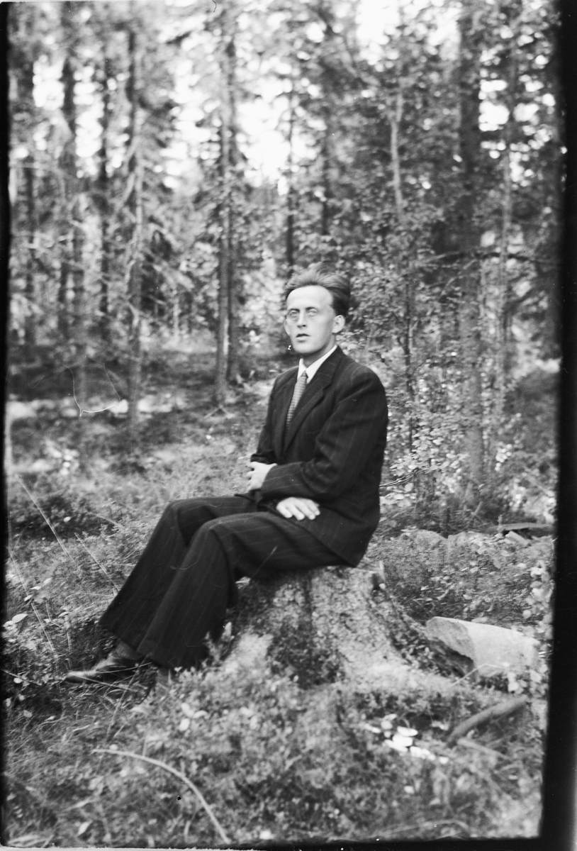 Håkon Prestkværn, Ukjent mann i dress på en stubbe i skogen.