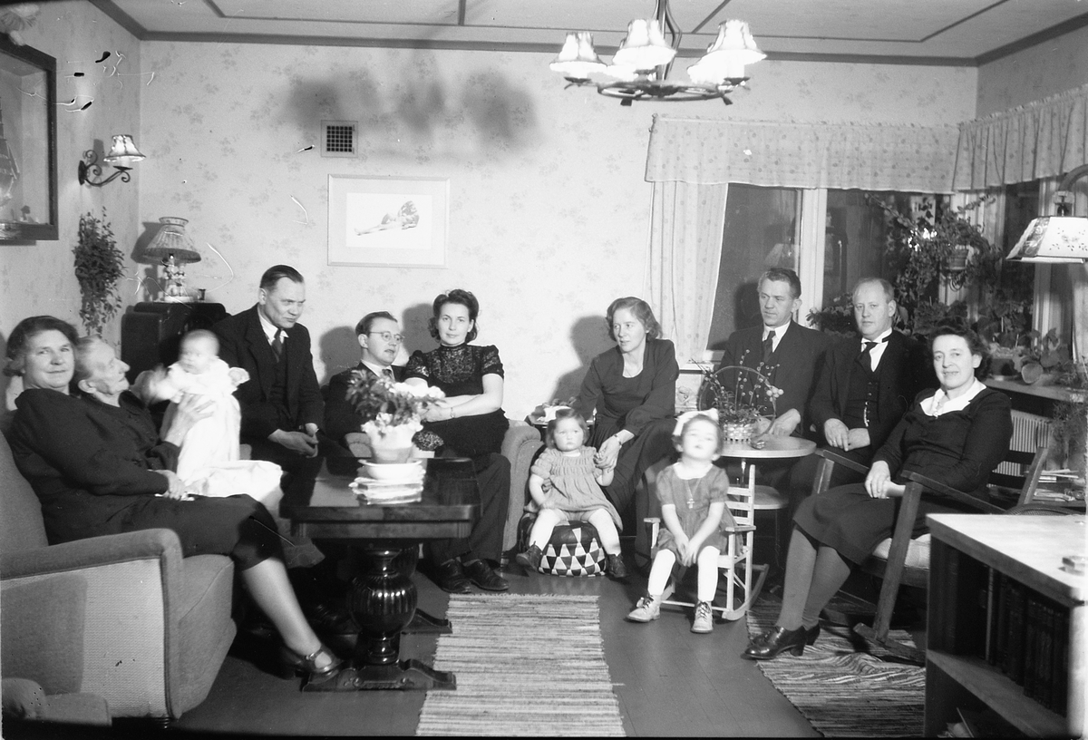 Håkon Prestkværn, Interiør, stue. Barnedåp. Familiegruppe. Dåpsselskap hos Haugen, meieriet på Moelv. Dåpsbarnet er Torhild.