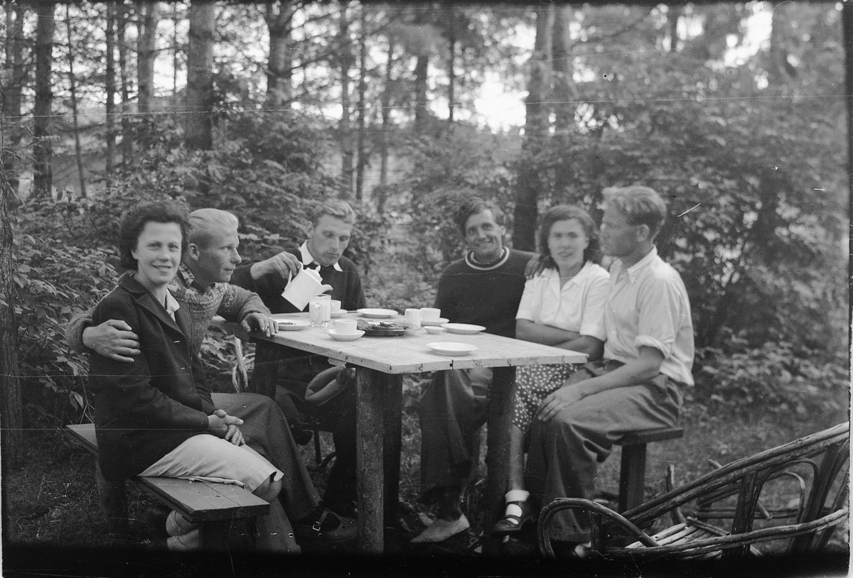 Håkon Prestkværn, Gruppe kvinner og menn drikker kaffe rundt et bord i skogen.