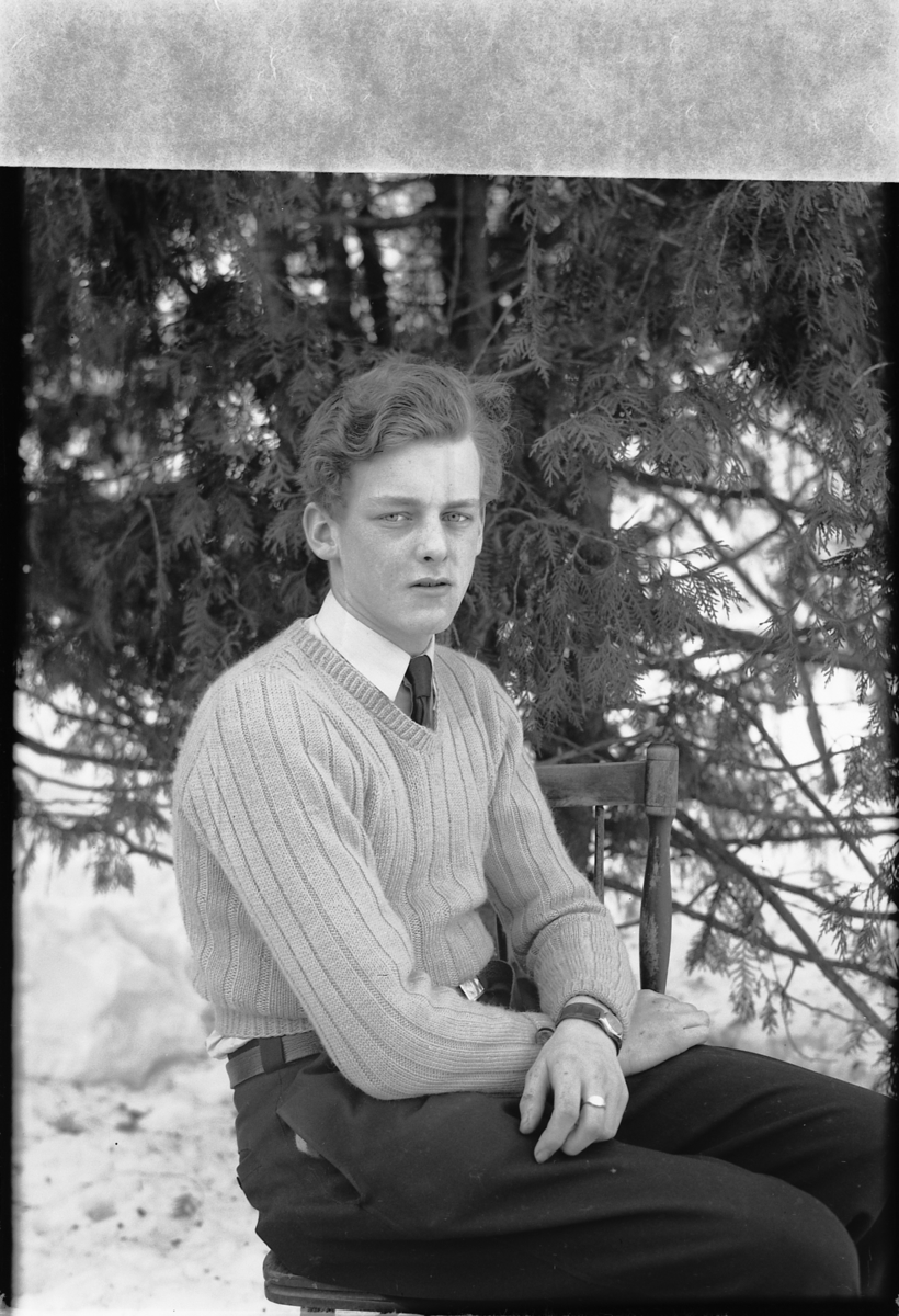 Håkon Prestkværn, Ukjent mann på en stol med et grantre i bakgrunnen.