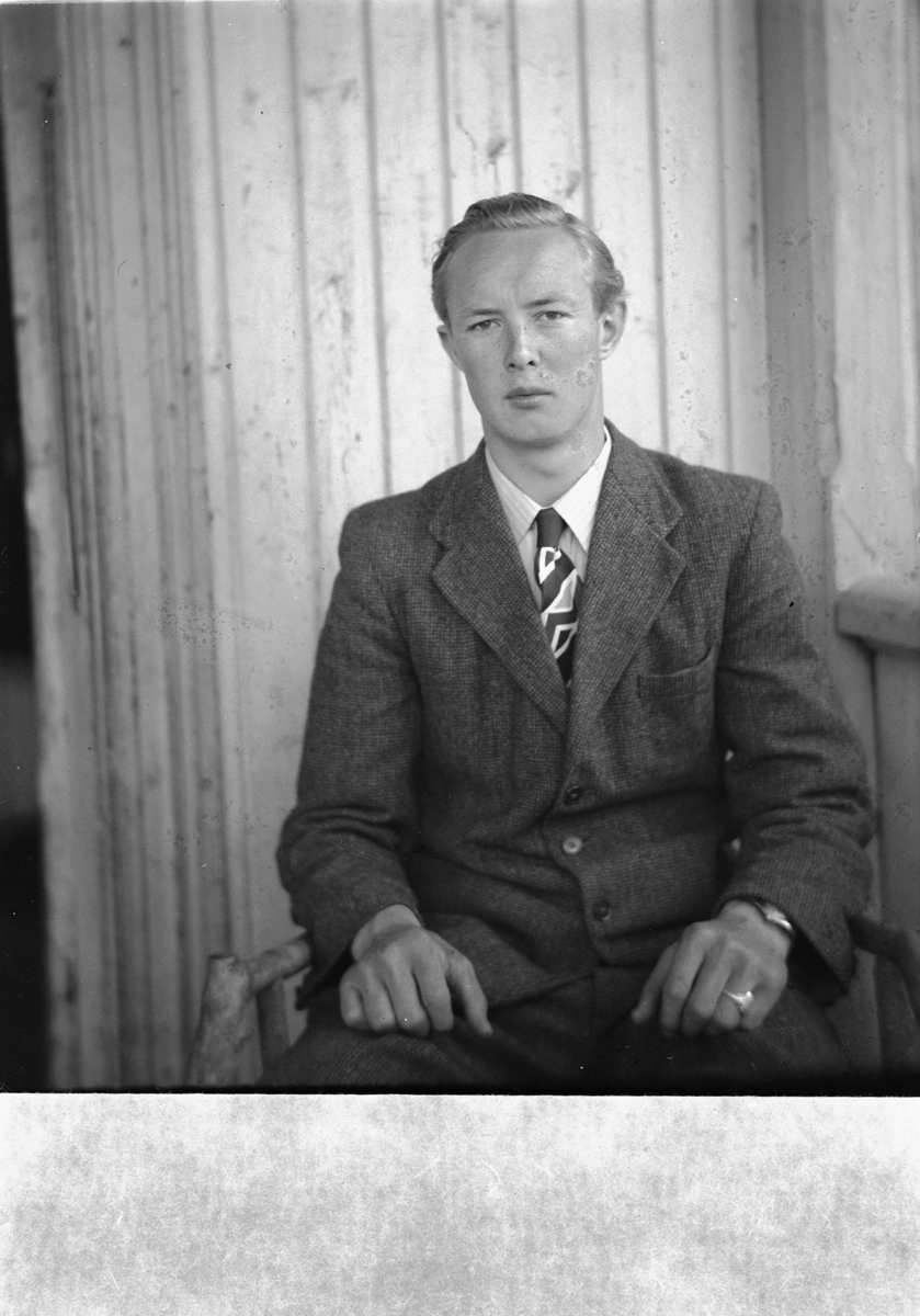 Håkon Prestkværn, Ukjent mann sitter i en stol på trammen.