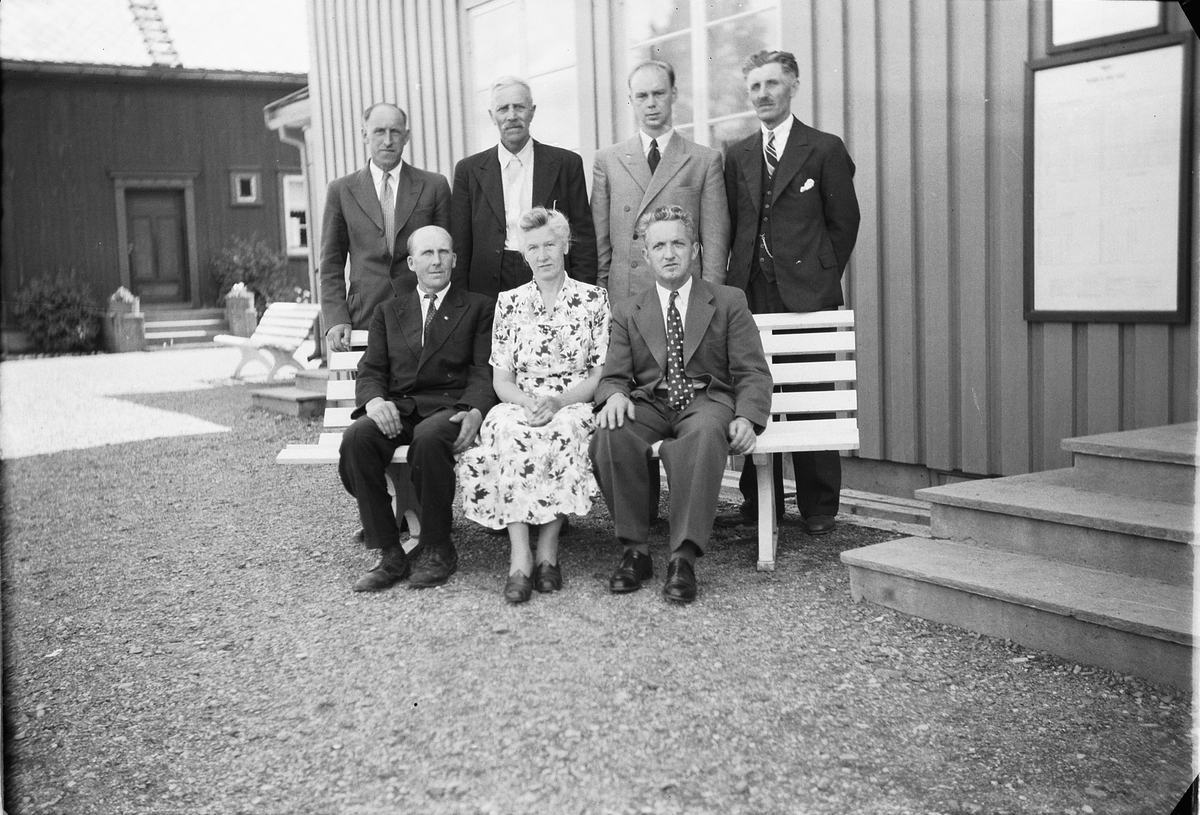 Håkon Prestkværn, Gruppe kvinner og menn foran et hus.