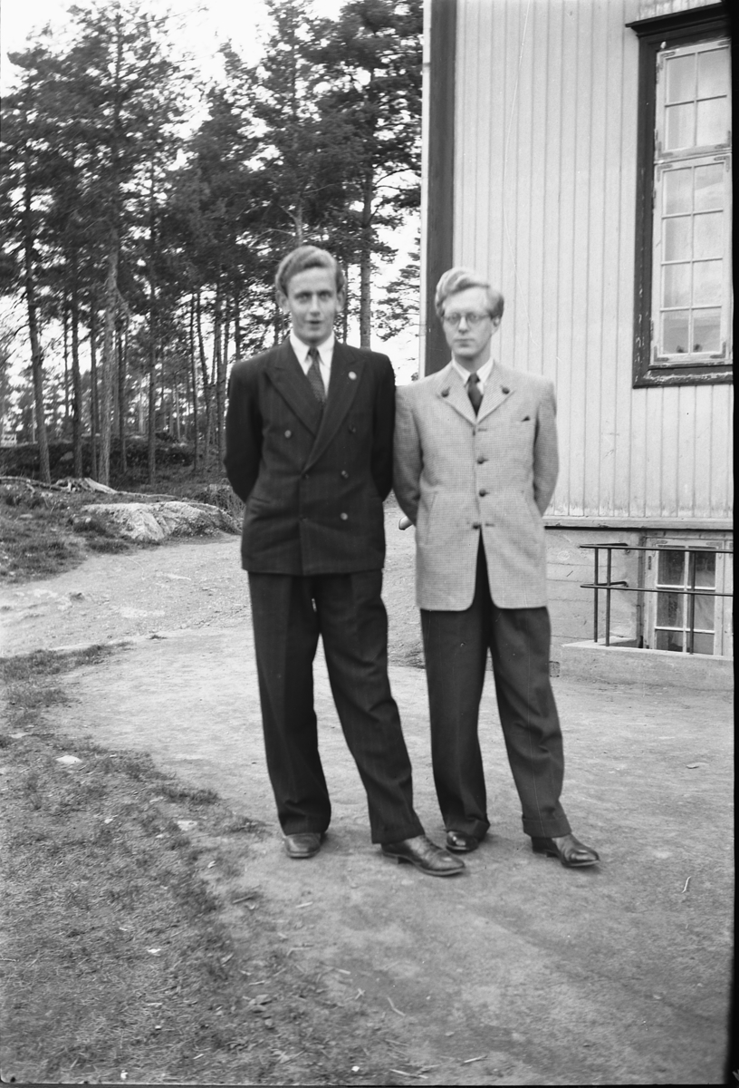 Håkon Prestkværn, To menn i dress foran ukjent bygning.