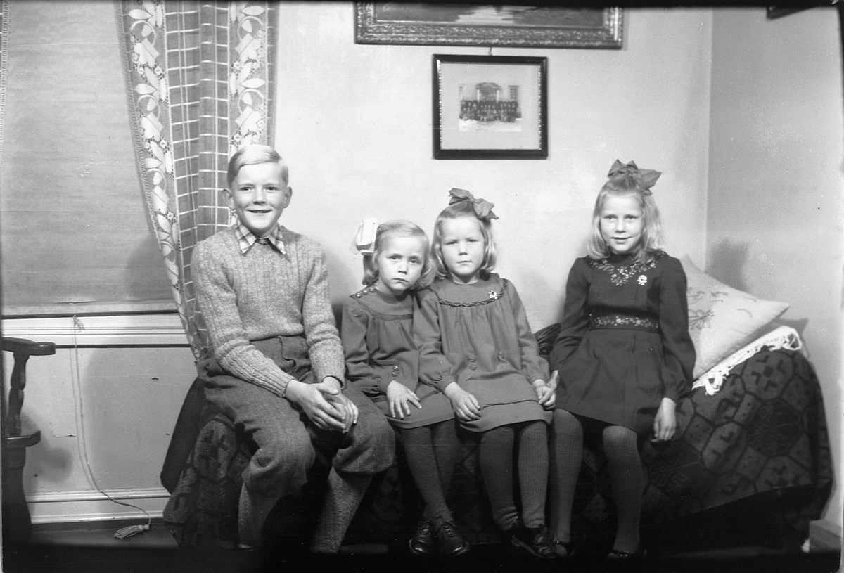 Håkon Prestkværn, Interiør, stue. En gutt med tre jenter sitter på en sofa.