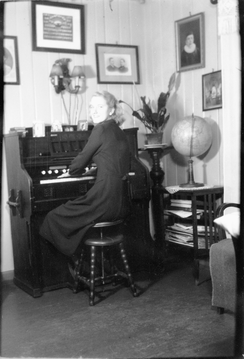Håkon Prestkværn, Interiør, stue. Ukjent kvinne spiller på et orgel.