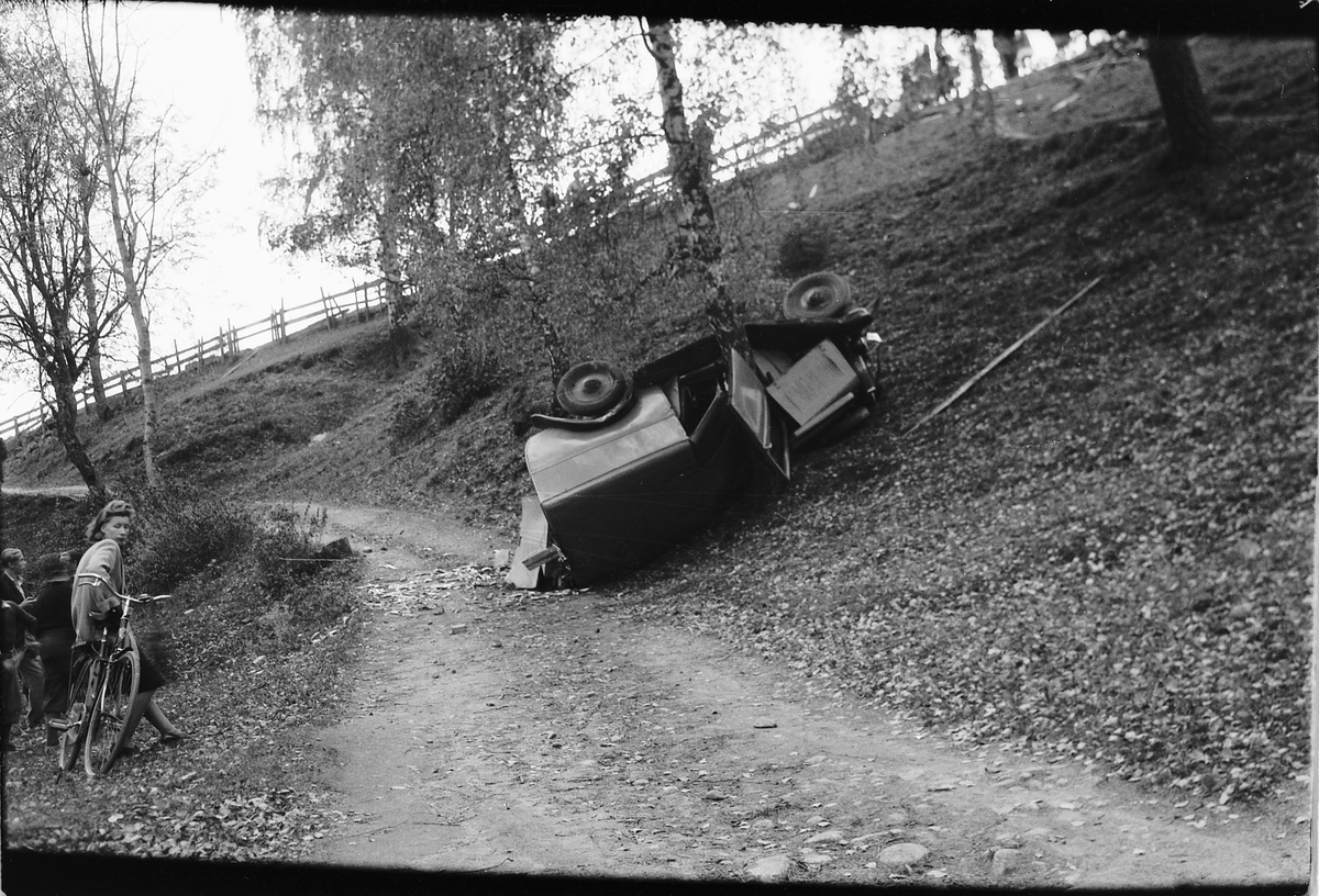 Håkon Prestkværn, Bilulykke. Varebil veltet i skråning. Moelv. John Strømman var uheldig og trillet ut over Lykkjebakken med sin fiskebil 1946-1947. Alt gikk imidlertid bra untatt med bilen en Opel P-4 , D-3357, ,som nærmest ble vrak. Minda Kleiven står t. v. med sykkel.