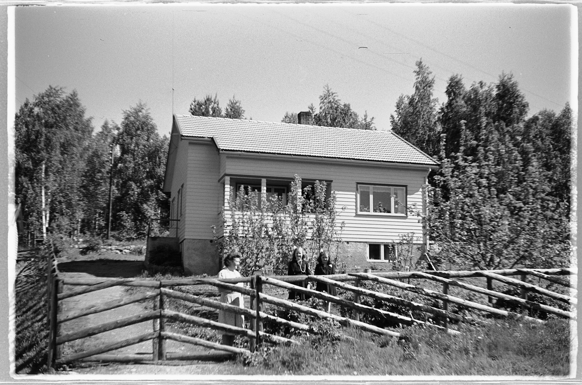Håkon Prestkværn, Tre personer ved et gjerde i hagen til et hus.