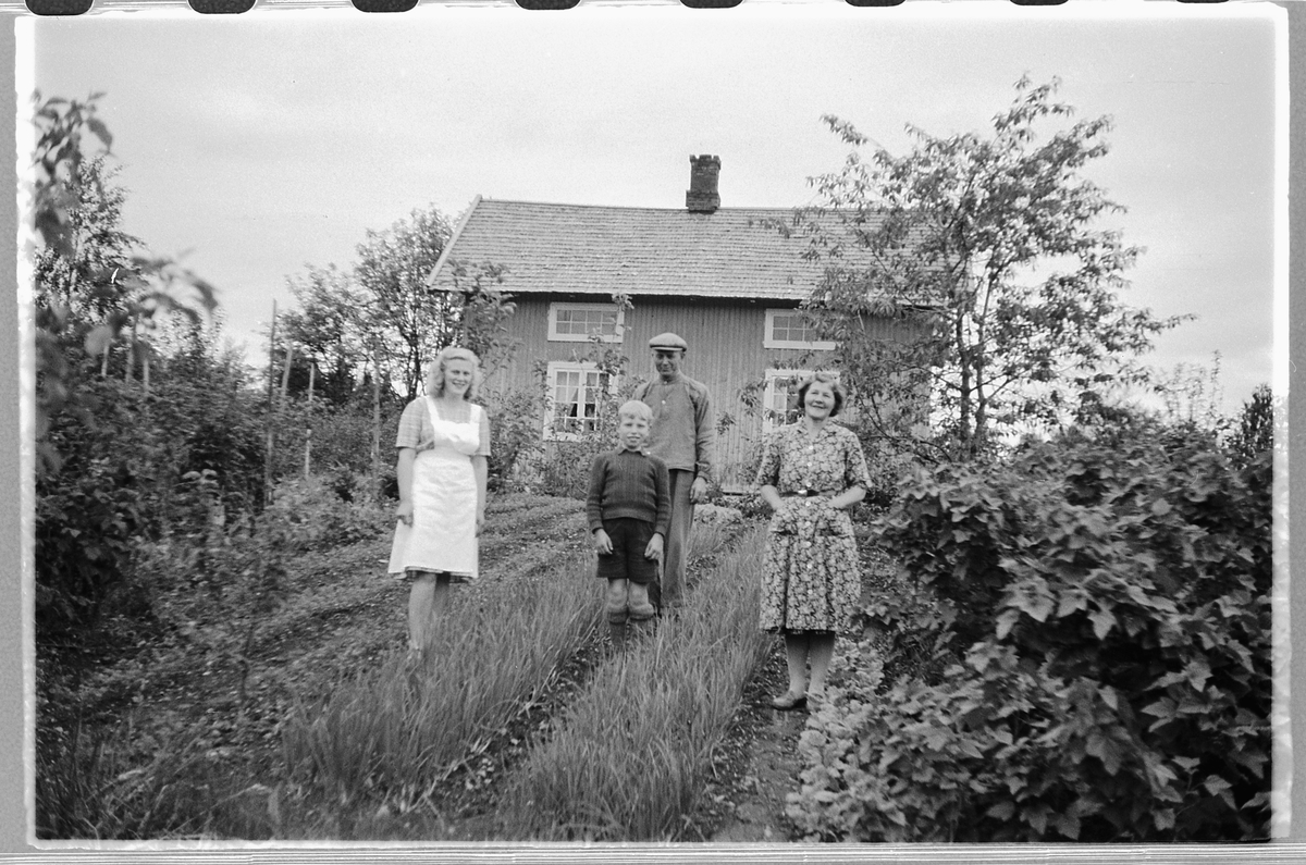 Håkon Prestkværn, To kvinner, en mann og en gutt i en hage.