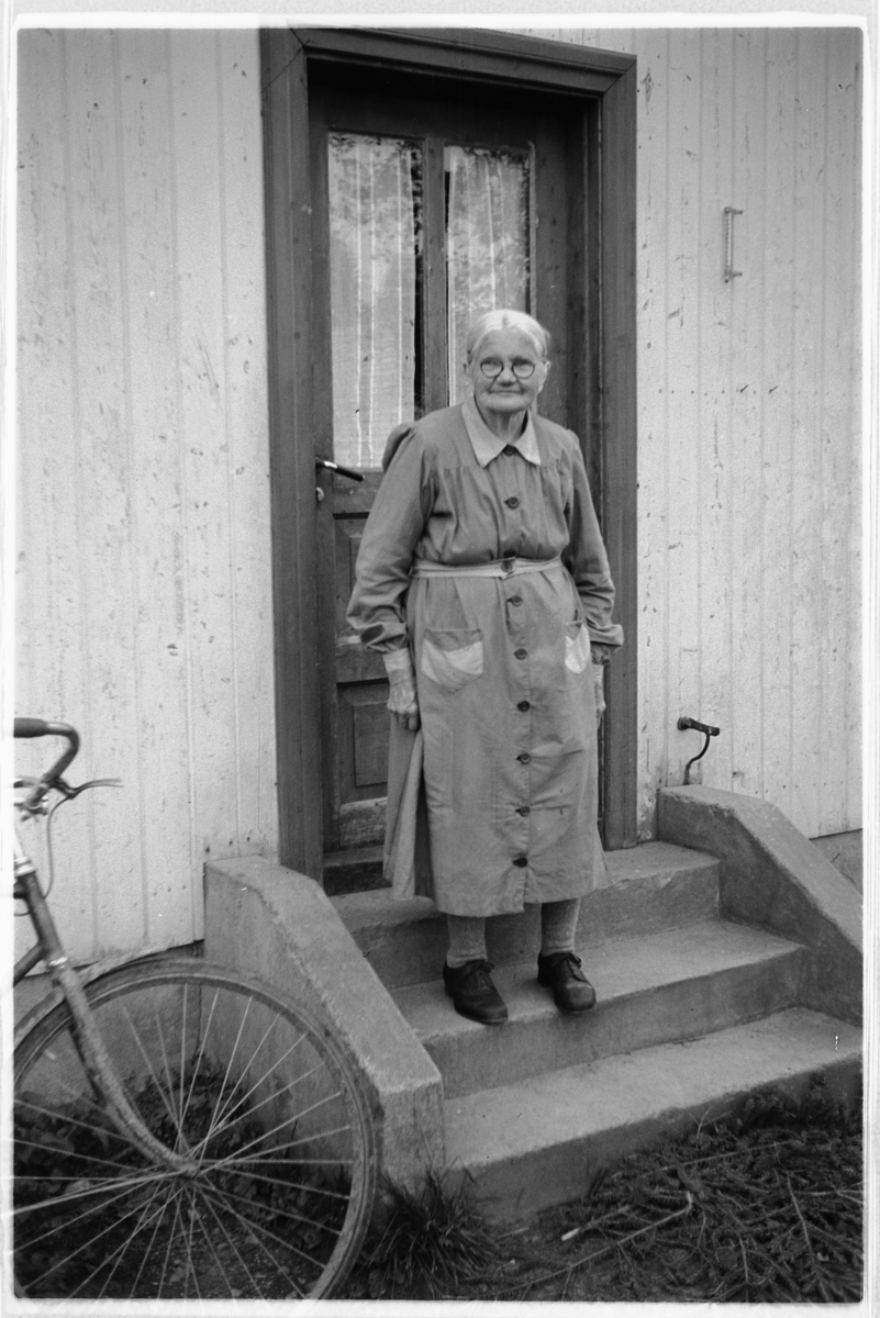 Håkon Prestkværn, Eldre kvinne på trappa til et hus, ukjent, Moelv.