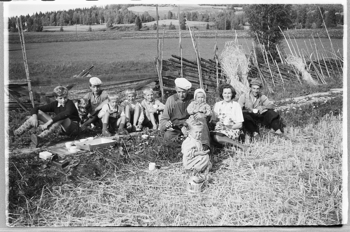 Håkon Prestkværn, Ukjente menn, ei kvinne og flere barn spiser niste på et jorde ved en skigard.