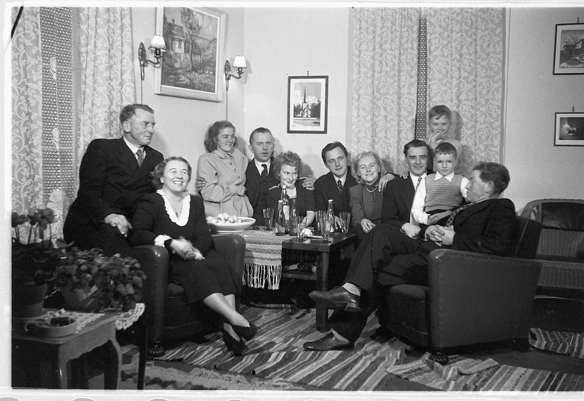 Håkon Prestkværn, Interiør, stue. Ukjent familiegruppe samlet rundt stuebordet.