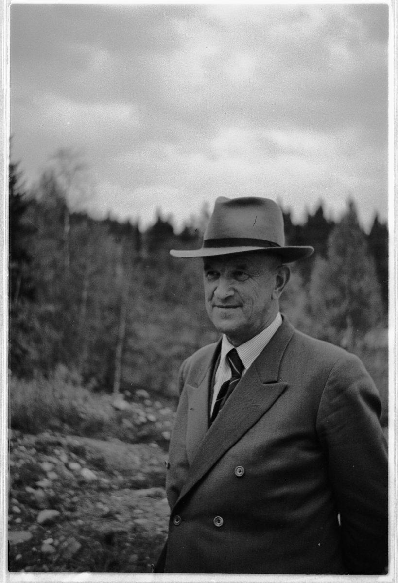 Håkon Prestkværn, Eksteriør, skog. Ukjent mann med dress og hatt.