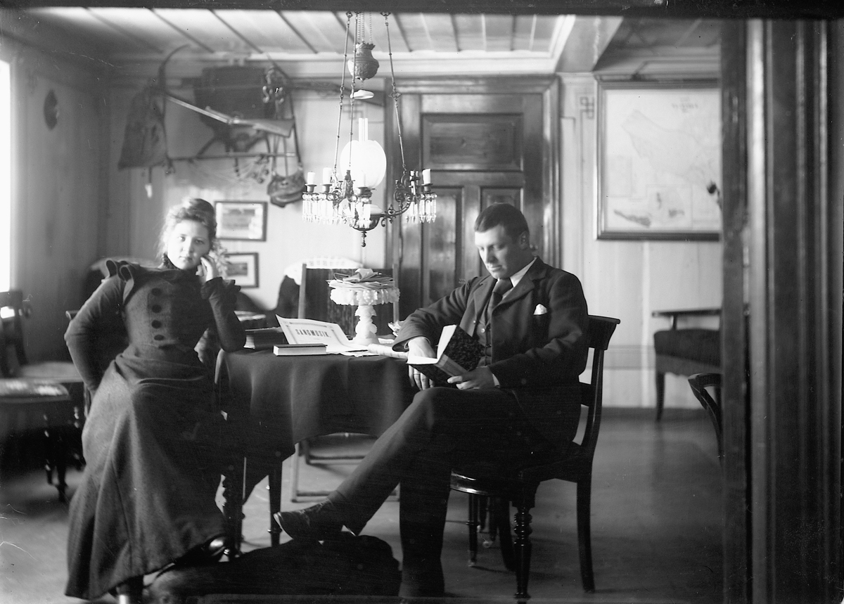 Kristoffer Horne, Interiør, stue. En kvinne og en mann sitter ved et bord.