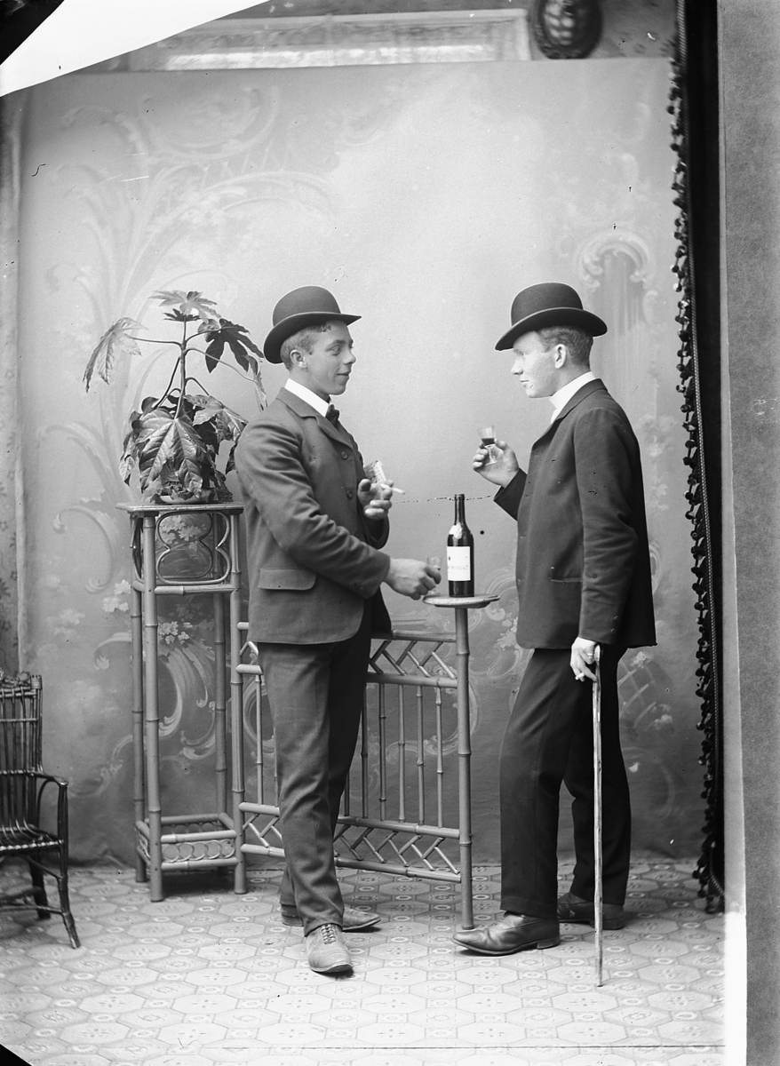 Ragnvald Andersen, Studio, gr. 2 To unge menn med hatt skåler med hverandre. Sigarett i hånda.