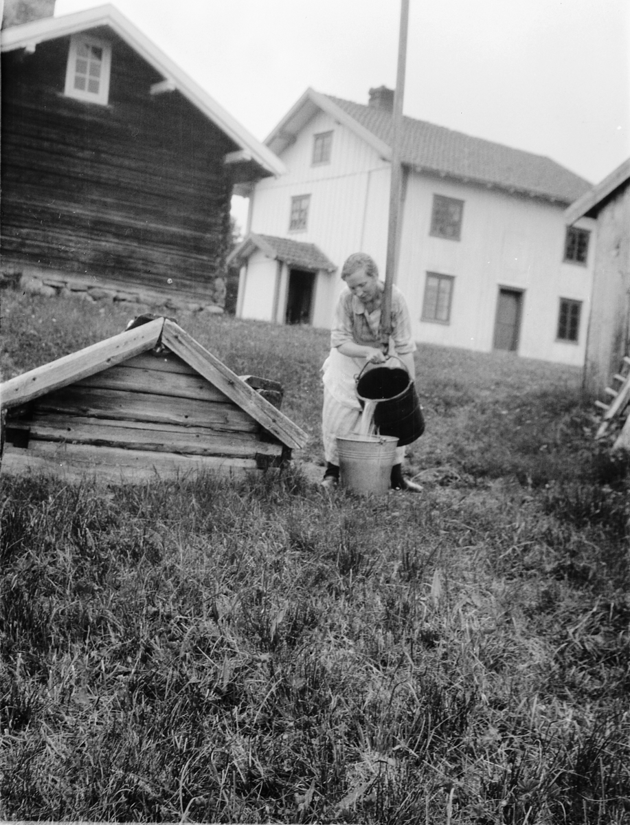 Ragnvald Andersen, Ukjent kvinne heller vann i ei sinkbøtte ved en vannpost, brønn.