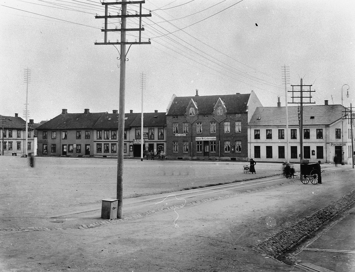 Hans Emil Erichsen, Østre Torg i Hamar med bebyggelsen langs Vangsvegen. Postkontor, Hamar Melkeforsyning, Agra Margarin, R. Eriksens Fotografiske Atelier. Folk på torget. Hest og kjerre.