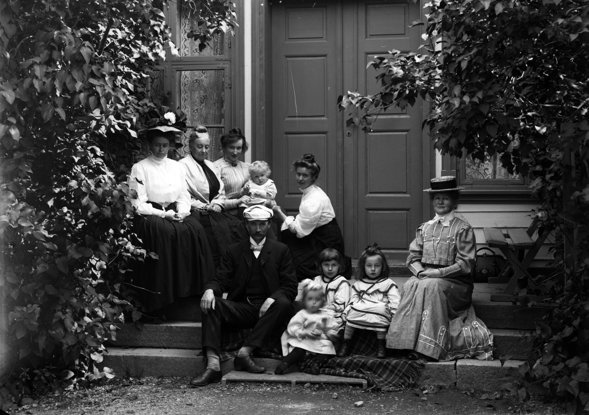 Martin Finborud, Familiegruppe, Mellbye, Grefsheim. Johan Egeberg Mellbye (1866-1954) sittende på trappa. Hans kone Emilie sittende på huk.