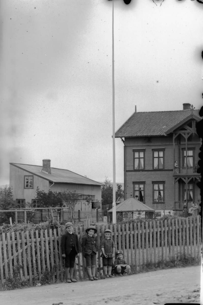 Hans Emil Erichsen, 4 ukjente barn forn stakkgjerdet i Parkgata, Hamar. Huset til stasjonsmester Christian Fredrik Lund.