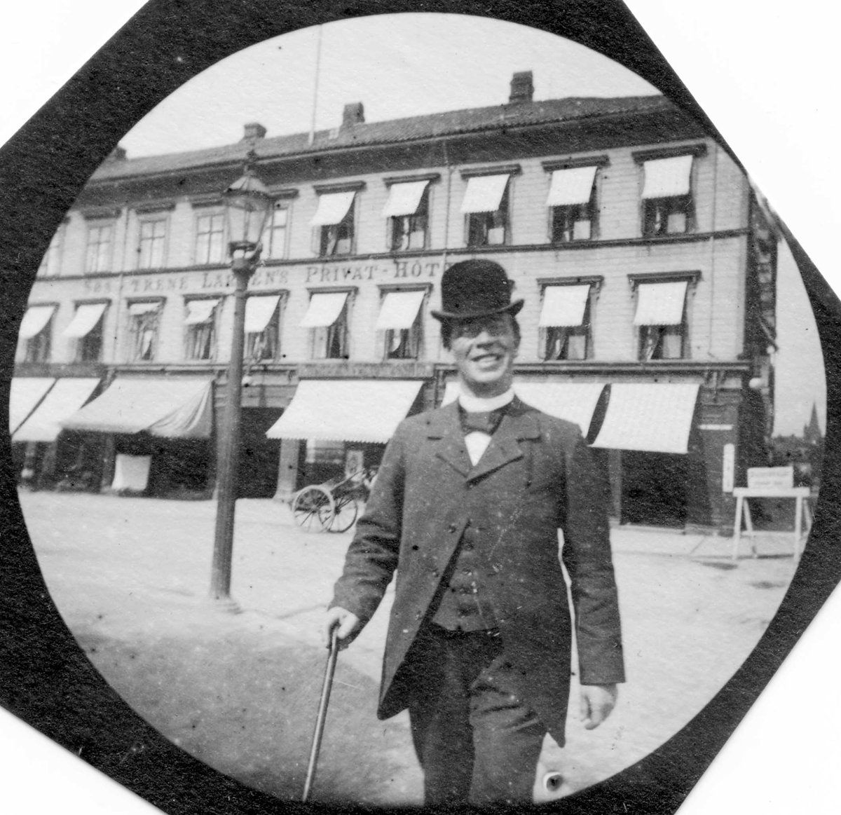 Fredrik Carl Mülertz Størmer, Adjunkt Kristiansen ("Kubein") med hatt, dress og stokk foran "Søstrene Larsen`s Privat-Hotel".
