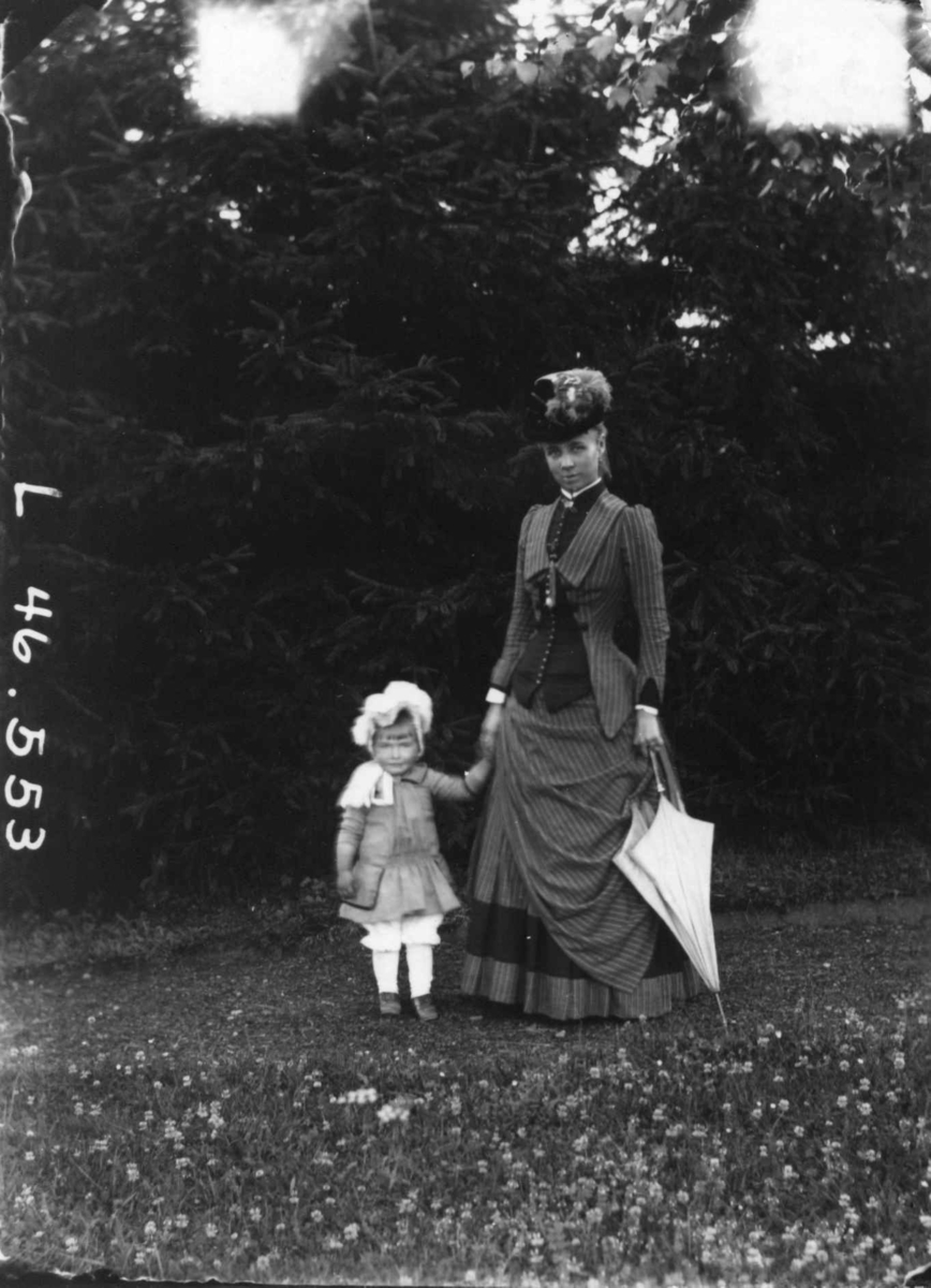 Fredrik Emil Faye, Portrett, fru Sigrid Faye med datter Anna (senere gift Treschow), 1884. Kvinne med pike og parasoll i hendene. Fra portrettserie av personer som bodde på eller besøkte Dal gård, Ullensaker, fotografert av gårdens eier, kammerherre Fredrik Emil Faye (1844-1903) i årene 1875-1900.