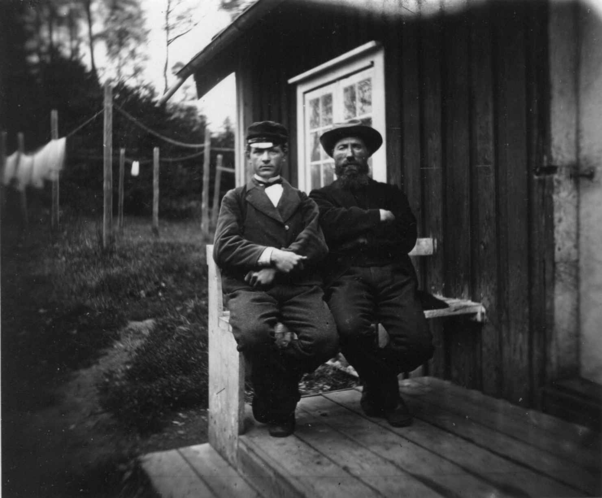 Fredrik Emil Faye, Husmannsfolk, to menn på benk foran hus. Fra portrettserie av personer som bodde på eller besøkte Dal gård, Ullensaker, fotografert av gårdens eier, kammerherre Fredrik Emil Faye (1844-1903) i årene 1875-1900.