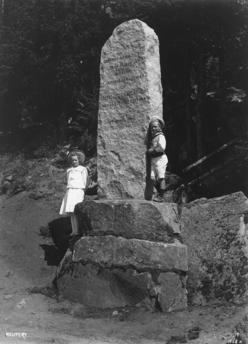 Hermann Christian Neupert, Hakadal, Nittedal, Akershus. 1910. Feltmanøver. Bauta. Gutt og pike ved denne.