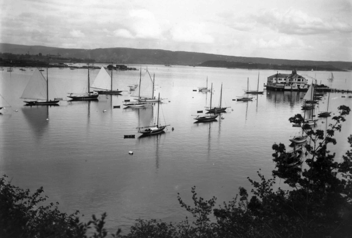 Hermann Christian Neupert, Frognerkilen, Bygdøy, Oslo 1908-1910. Oversiktsbilde. Utsikt mot Dronningen. Seilbåter ved bøyer på vannet.