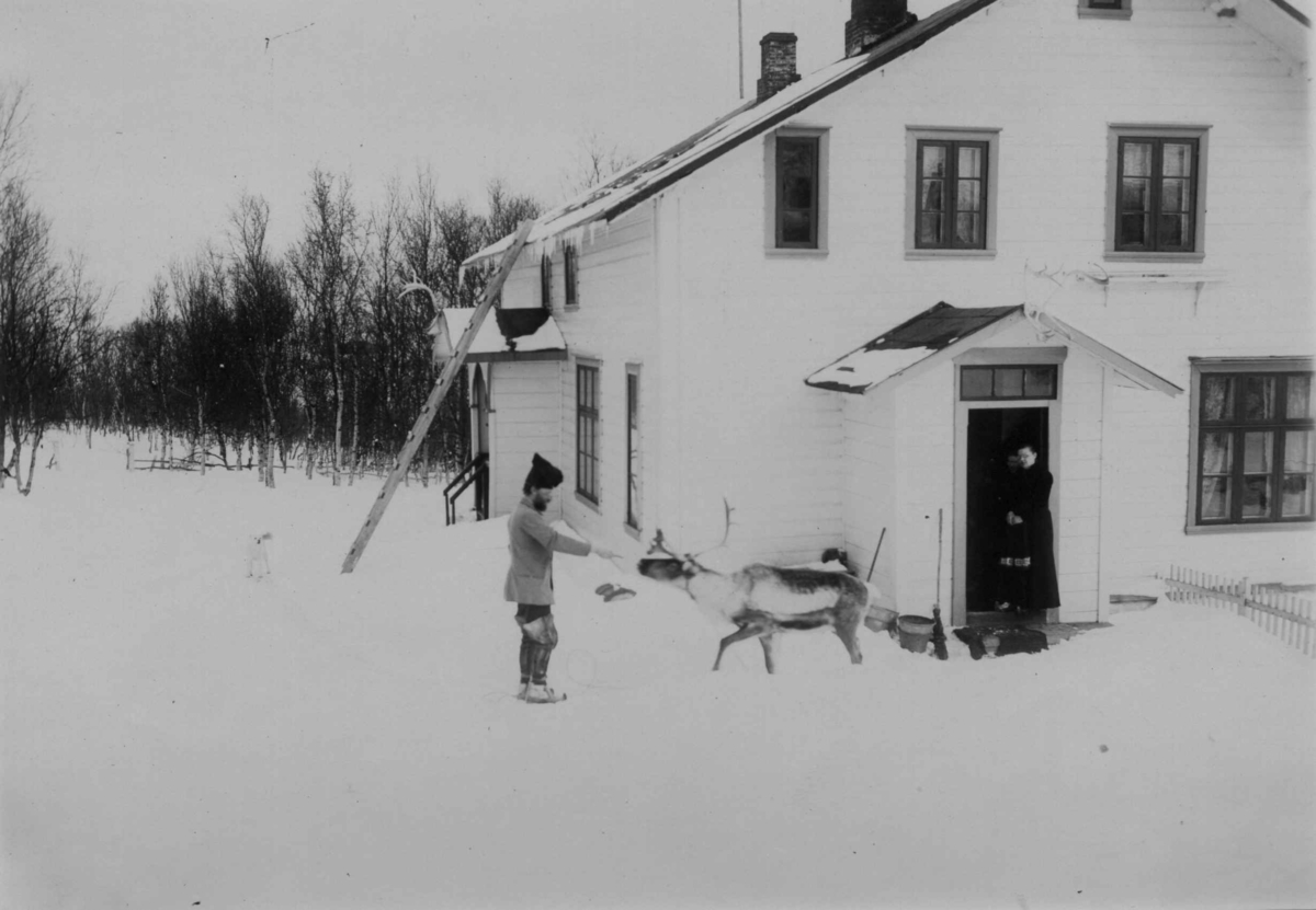 Ellisif Rannveig Wessel, To personer og et reinsdyr utenfor legeboligen Solheim hvor Dr. Andreas B. Wessel og Ellisif Wessel bodde. Kirkenes, Sør-Varanger, Finnmark, 1899. Kvinne står i døren.