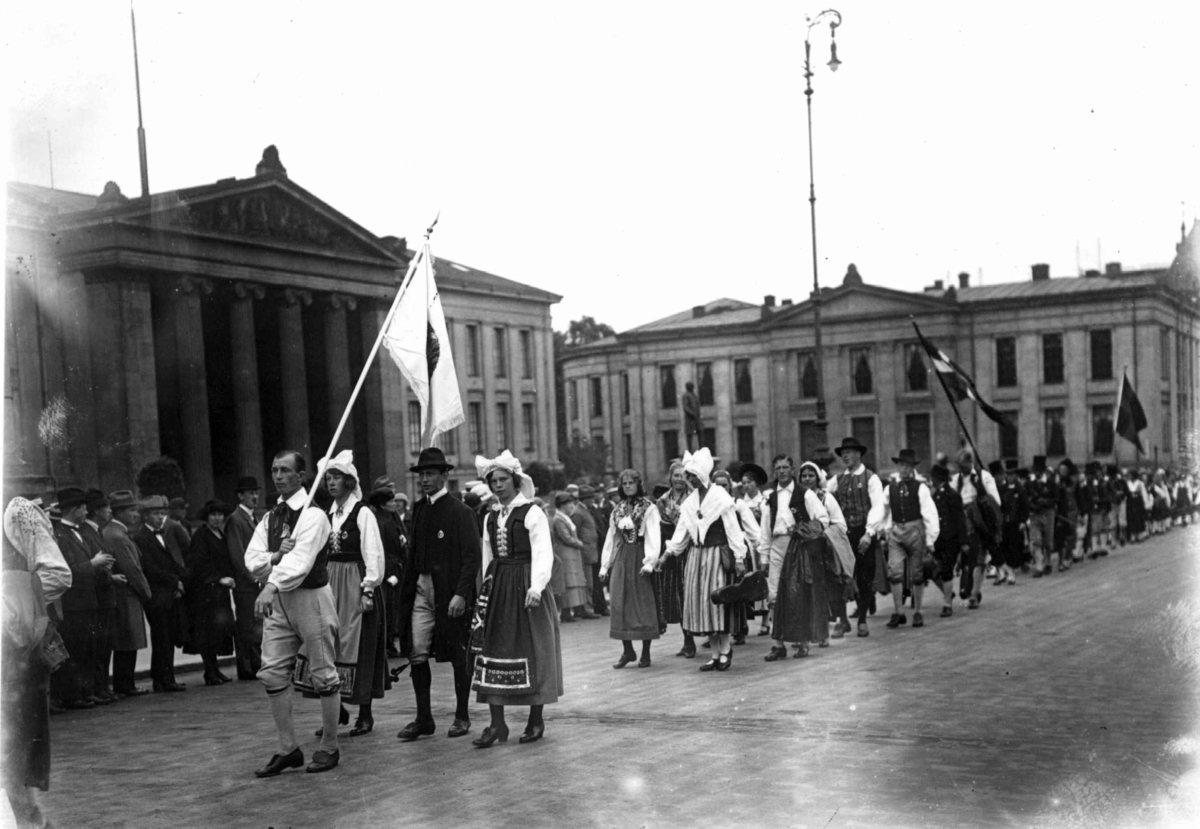 Hermann Christian Neupert, Nordisk Folkedansstevne. Karl Johans gate ved Universitetet - Oslo. 1925. Opptog av norske og svenske folkedansere. Flagg. Publikum.