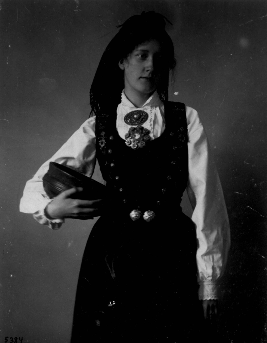 Hermann Christian Neupert, Kvinnedrakt fra Tinn, Telemark. 1927. Kvinne med bolle i hånden.